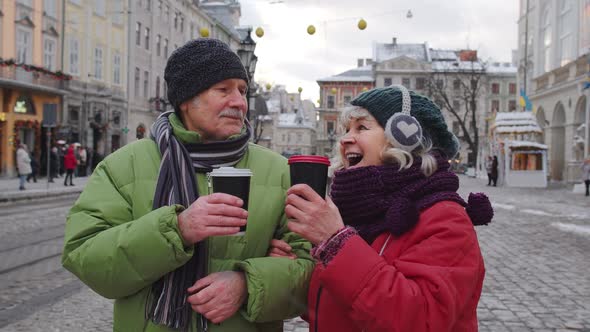 Senior Old Couple Tourists Grandmother Grandfather Traveling Drinking Hot Drink Tea in City Center