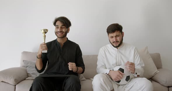 Two Indian Men in Black and White Football Fans Suit in a Modern Bright Room