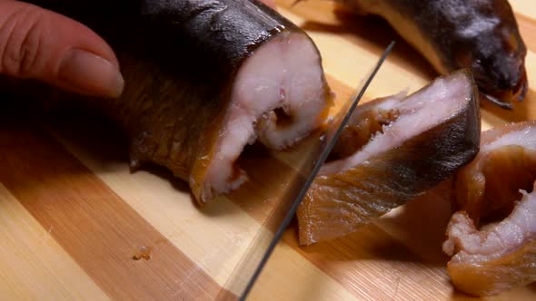 Close Up of Hands Cutting Smoked Eel Into Portions