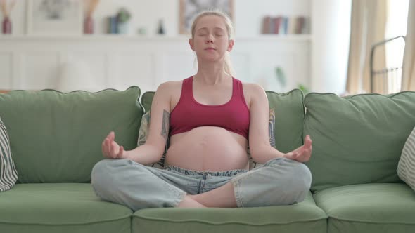 Meditating Pregnant Woman Doing Yoga While Sitting on Sofa