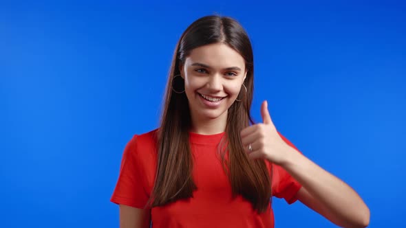 Cute Woman Showing Thumb Up Sign Over Blue Background