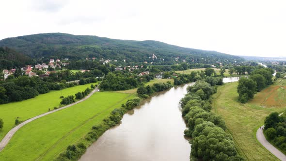 Aerial Drone Shot  a Large River Runs Through a Hilly Rural Area with Villages on a Sunny Day