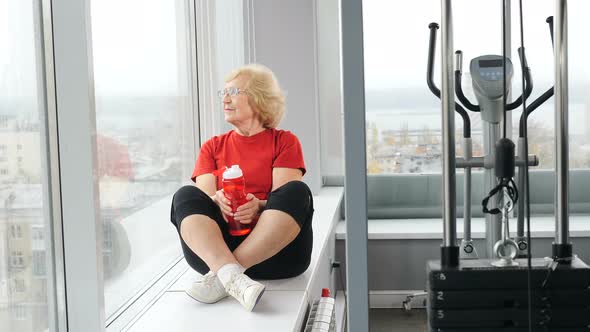 Pretty Active Retired Woman in Red Tshirt Sitting on Window Sill in Gym