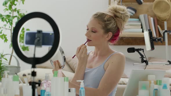 Blonde smiling woman influencer blogger recording a video tutorial on smartphone camera