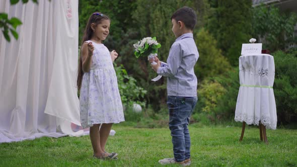 Excited Middle Eastern Pretty Girl Receiving Wedding Bouquet From Cute Boy at Altar