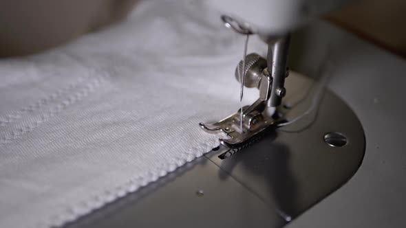 Close-up of Sewing Machine Needle with Thread Pierces Fabric in Slow Motion