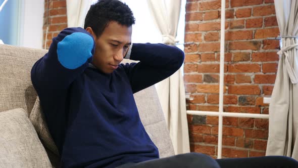 Neck Pain, Tired Young African Man Sitting on Sofa, Loft