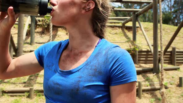 Fit woman drinking water after workout during obstacle course