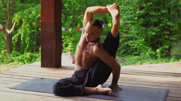 The Man in the Park Demonstrates Exercises with Yoga.