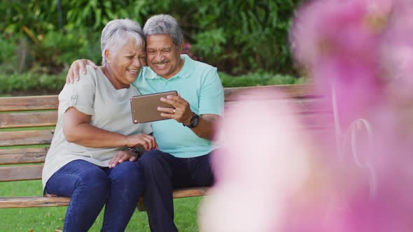 Video of happy biracial senior couple using tablet in garden