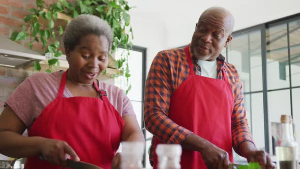 Happy african american senior couple cooking together in kitchen