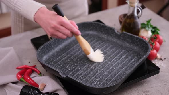 Woman Spreading Cooking Olive Oil on the Frying Pan with a Brush