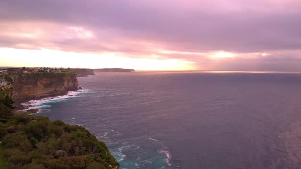 Perfect golden hour sunrise drone shot of ocean and cliff with velvet sky early in a beautiful morni