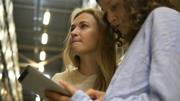 Serious Ladies Choose Goods Standing in Wholesale Warehouse