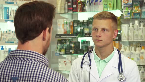 Doctor Talking To Patient with Headache in Drugstore