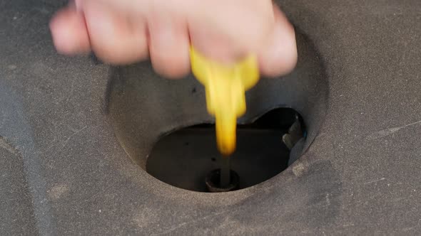 Close-up of checking the oil level on the yellow knob oil dipstick in a used car