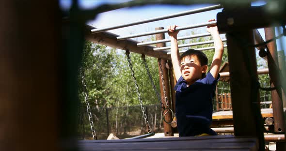 Schoolboy playing on monkey bar in playground