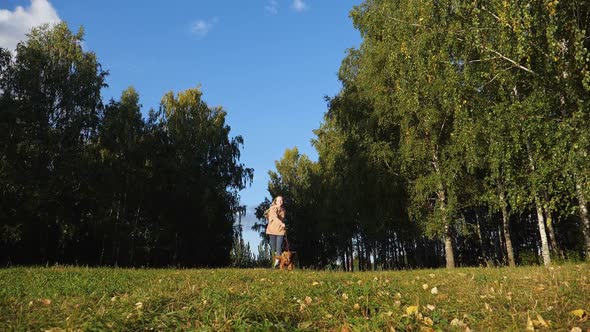 Girl Holds Furry Russian Spaniel on Red Leash and Runs