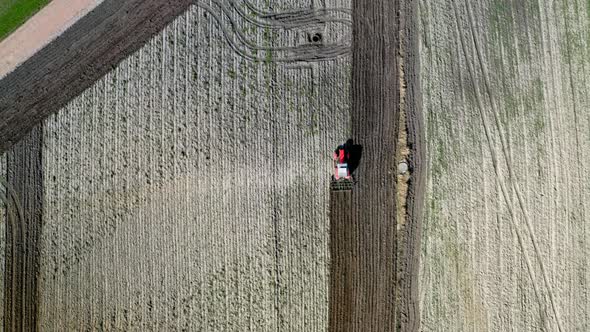 Red tractor plowing field, aerial view in spring