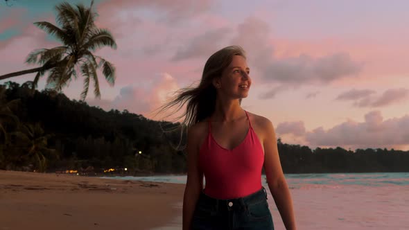 Beautiful Smiling Girl Walking on Sand Beach By Sea During Sunset