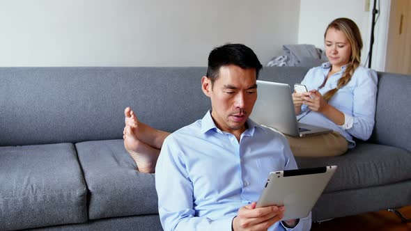 Man using digital tablet while woman using mobile phone