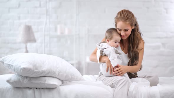 Happy Family Young Woman and Cute Kid Relaxing Together at Morning Bedroom Interior Background