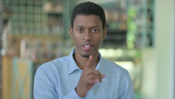 Portrait of Young African Man Putting Finger on Lips