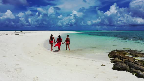 Beautiful women relaxing on idyllic lagoon beach voyage by shallow water and bright sandy background