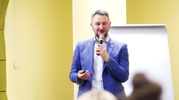 Half-length portrait of a businessman talking to the microphone during the business forum.