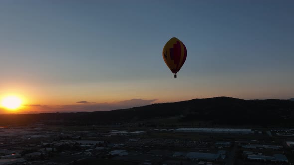 Wide shot of a hot air balloon soaring through the golden sky.