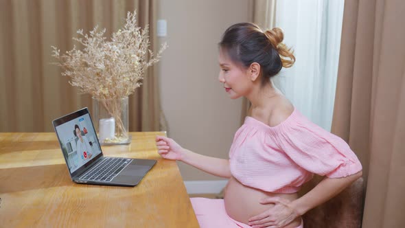 Asian young pregnant woman talking virtual online with medical doctor.