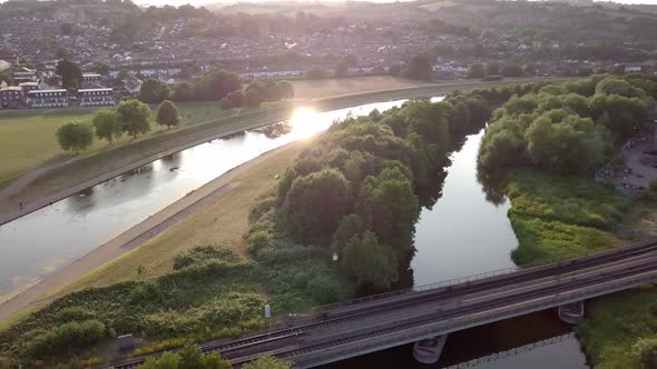 Sun reflecting in River Exe at sunset, Aerial pull over railway crossing water