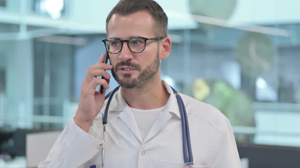 Middle Aged Male Doctor Talking on Smartphone