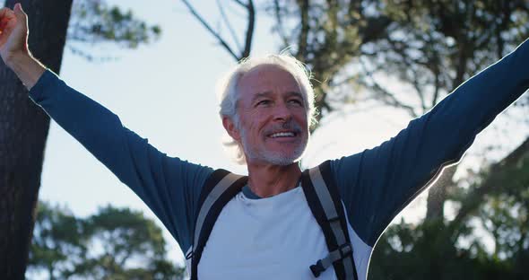 Senior man standing with arms up in the forest