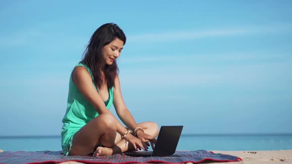 Portrait of Beautiful Woman Sitting on Beach with Laptop and Working