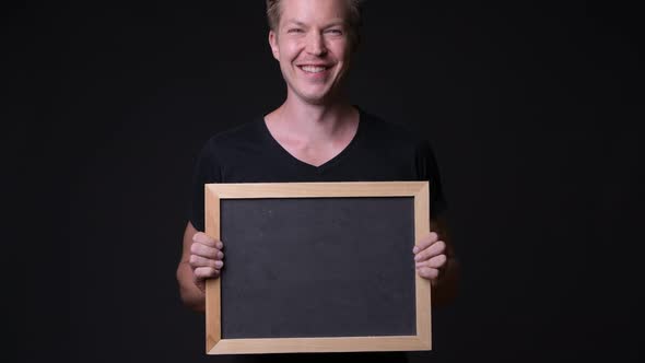 Young Handsome Man Holding Blackboard Against Black Background