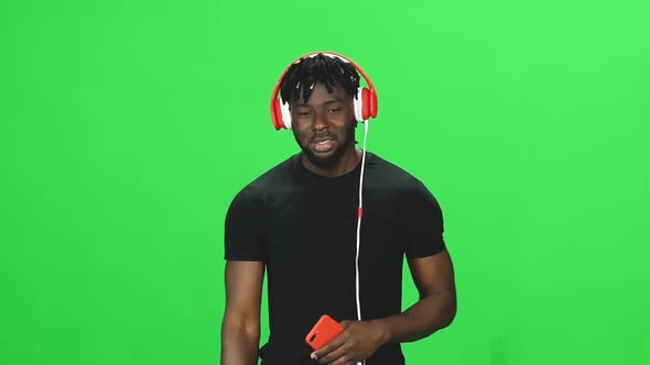 Portrait African Man in Red Headphones Walking and Listening To Music Vie Mobile at GreenScreen