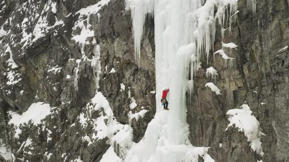 Aerial one lone climber scaling frozen cascade Maineline, Mount Kineo 4K