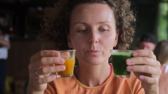 A Woman Sitting in a Catering Establishment and Tasting Two Drinks