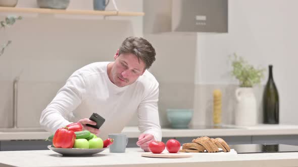 Man Taking Picture of Fruits on Smartphone in Kitchen
