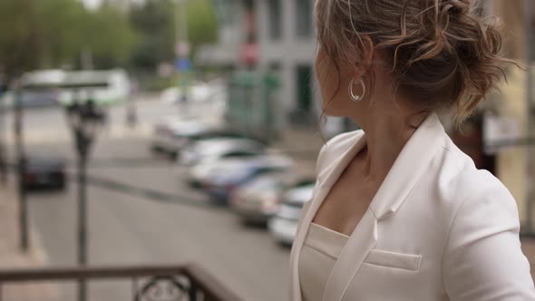 an Attractive Romantic Woman in White Clothes Against the Background of the City