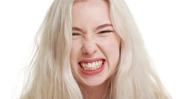 Angry Blonde Caucasian Teenage Girl Fixedly Looking Grimacing on White Background in Slowmotion