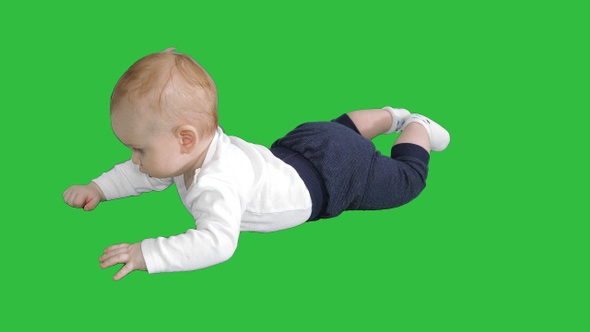 Baby lays on his stomach and holds his head on a Green