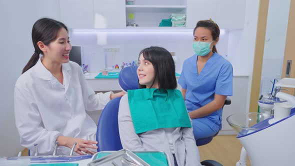 Asian female dentist welcome and recommend dental treatment plan service to young patient in clinic.