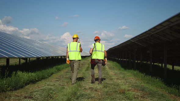 Unrecognizable Male Workers Walking and Inspecting Solar Panels