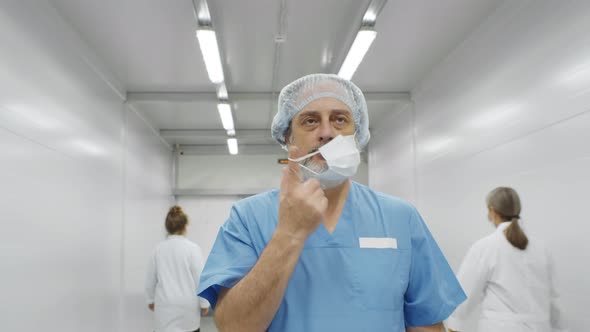 Senior Tired Male Surgeon Walking Through Hospital Corridor After Difficult Surgery