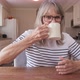 Retired woman drinking her morning coffee while sitting at kitchen table - VideoHive Item for Sale
