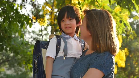 Asian Mother Holding Her Son While Walking In The Park Back To School Concept