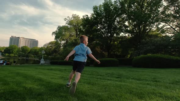 The Boy Runs on the Grass in the Park