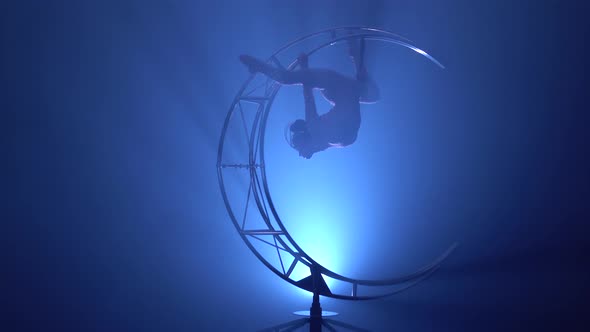 Gymnast in a Brilliant Costume Performs Tricks on a Special Design Moon